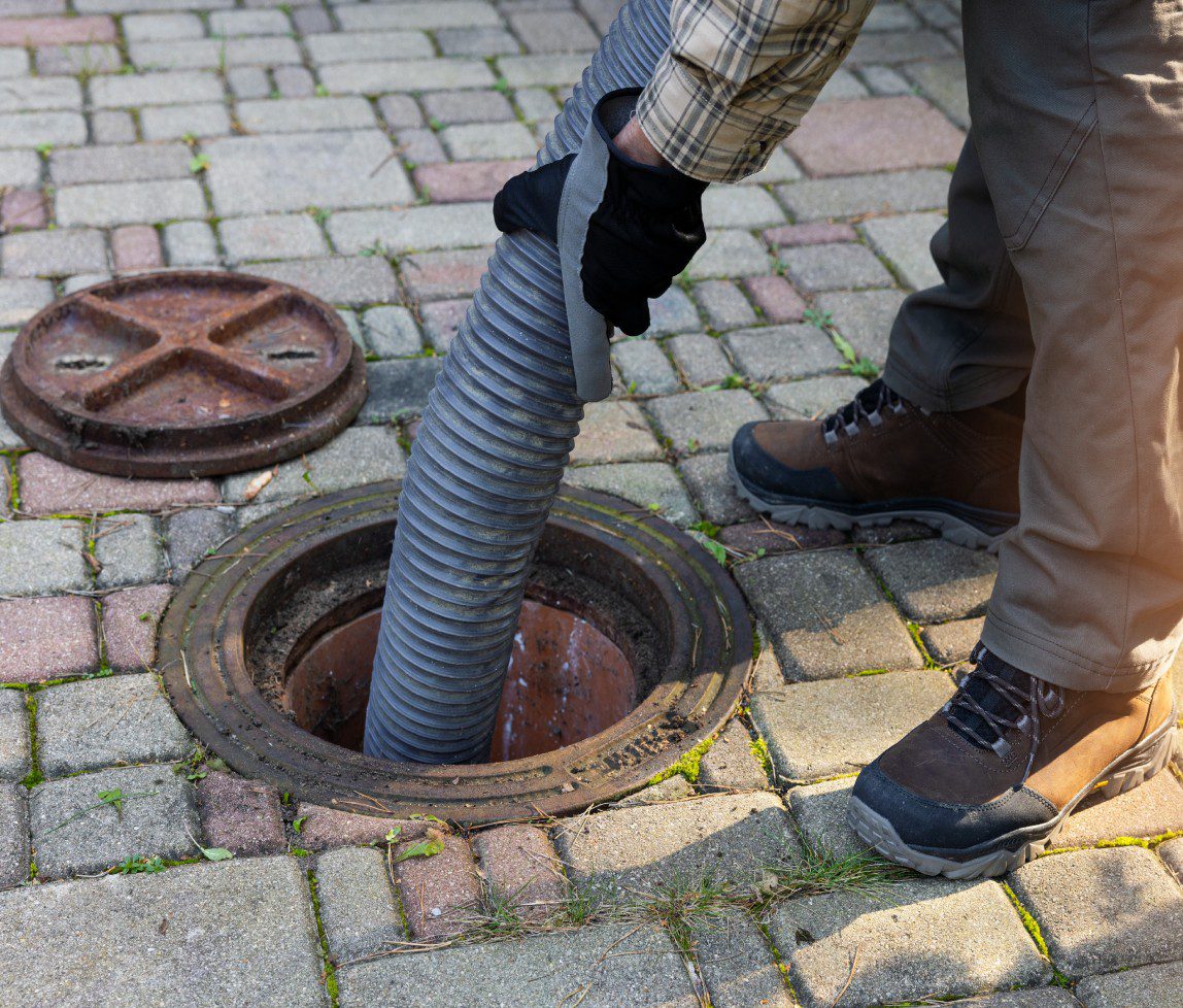 Person using a flexible hose to clean a sewer or drain.