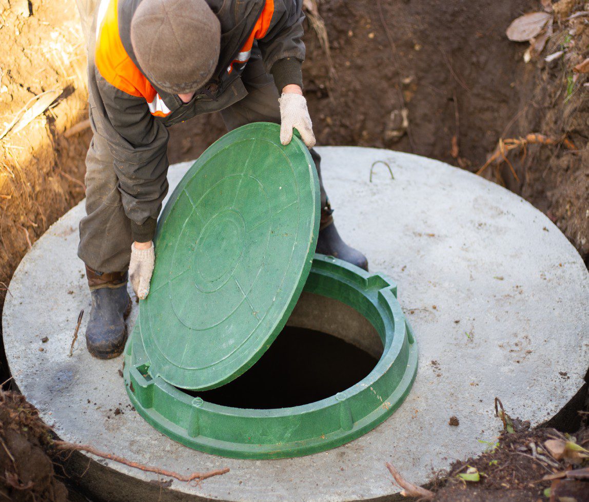 Worker opening a green hatch to a concrete underground tank.
