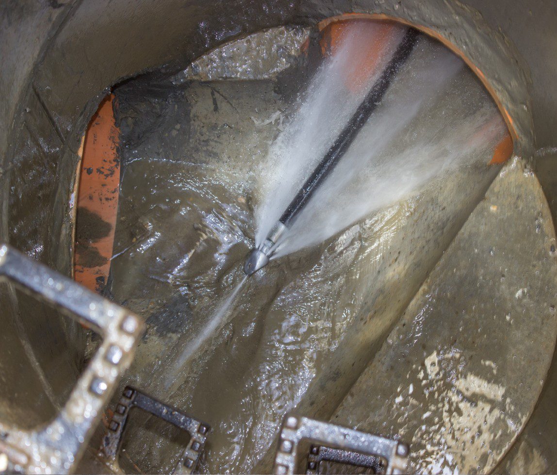 Inside view of a large industrial pipe with flowing water and metal components.